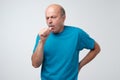 Mature hispanic man in blue t-shirt man coughing being ill.