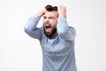 Mature hispanic man pulling his hair in hysteria having troubles at work