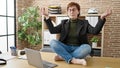 Mature hispanic woman business worker doing yoga meditation on the table at office Royalty Free Stock Photo