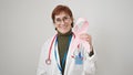 Mature hispanic woman doctor holding breast cancer awareness pink ribbon over isolated white background Royalty Free Stock Photo