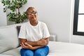 Mature hispanic woman sitting on the sofa at home skeptic and nervous, disapproving expression on face with crossed arms Royalty Free Stock Photo