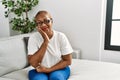 Mature hispanic woman sitting on the sofa at home thinking looking tired and bored with depression problems with crossed arms Royalty Free Stock Photo