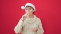 Mature hispanic woman smiling confident wearing christmas hat drinking a glass of white wine over isolated red background Royalty Free Stock Photo