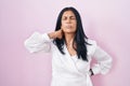 Mature hispanic woman standing over pink background suffering of neck ache injury, touching neck with hand, muscular pain Royalty Free Stock Photo