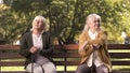 Mature ladies sitting separately on bench in park, friends argued and quarreled