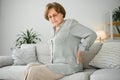 mature lady sitting on bed and touching her back, radiculitis and pain Royalty Free Stock Photo