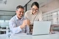 Happy diverse professional employees working in office using laptop, talking. Royalty Free Stock Photo