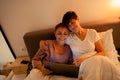 Mature lesbian couple hugging and using laptop in bed