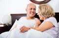 Mature loving couple lounging in bed after awaking cuddling