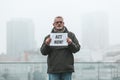 Mature male activist with a placard on the background of the city. Single picket