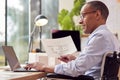 Mature Male Architect In Wheelchair Working In Office At Desk Studying Plans For New Building Royalty Free Stock Photo