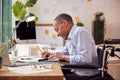 Mature Male Architect In Wheelchair Working In Office Studying Plans For New Building Royalty Free Stock Photo