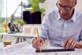 Mature Male Architect Working In Office At Desk On Plans For New Building Royalty Free Stock Photo