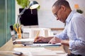 Mature Male Architect Working In Office With Model On Desk Studying Plans For New Building Royalty Free Stock Photo