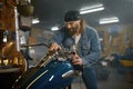 Mature male biker examining his new motorbike standing with garage