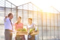 Mature male biochemist discussing with female coworkers against greenhouse Royalty Free Stock Photo