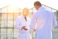 Mature male biochemists discussing while standing against clear blue sky