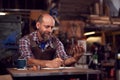 Mature Male Blacksmith Wearing Apron Working On Design In Forge