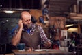 Mature Male Blacksmith Working On Design In Forge Whilst Using Mobile Phone Royalty Free Stock Photo