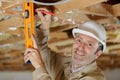 mature male builder using spirit level on ceiling joist Royalty Free Stock Photo