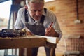 Mature Male Carpenter In Garage Workshop Marking Wood With Pencil Royalty Free Stock Photo