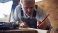 Mature Male Carpenter In Garage Workshop Marking Wood With Pencil Royalty Free Stock Photo