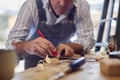 Mature Male Carpenter In Garage Workshop Marking Wood With Pencil And Steel Ruler