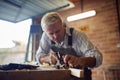 Mature Male Carpenter In Garage Workshop Planing Piece Of Wood Royalty Free Stock Photo