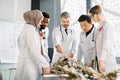 Mature male Caucasian teacher in class, holding a pencil and teaching human skeleton anatomy, using artificial skeleton