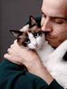 Mature male cradles a small white cat in his arms