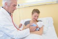 Mature male doctor examining baby girl with mother watching Royalty Free Stock Photo