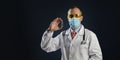 Mature male doctor hold a vaccine in hand in medical protective mask and goggles Royalty Free Stock Photo