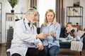 Mature male doctor , talking with woman about taking of medicines during home visit of sick boy. Royalty Free Stock Photo