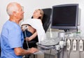 Mature male doctor using ultrasound scan examining female patient in modern hospital Royalty Free Stock Photo