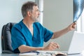 Mature male doctor working on laptop computer, sitting in medical office. Royalty Free Stock Photo