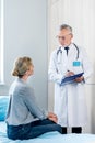 mature male doctor writing in clipboard near female patient Royalty Free Stock Photo