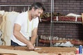 Mature male dressmaker cutting fabric in design studio