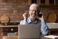 Mature male expert speak by phone distracted from laptop screen