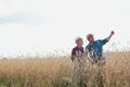 Mature male farmer showing showing wheat corp to senior farmer in field