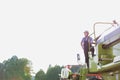 Mature male farmer standing on harvester in field Royalty Free Stock Photo