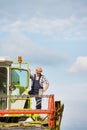 Mature male farmer standing on harvester in field Royalty Free Stock Photo