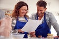 Mature Male And Female Adult Students Looking At Recipe In Cookery Class In Kitchen