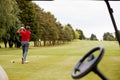 Mature Male Golfer Hitting Tee Shot Along Fairway With Driver Viewed Through Buggy Window