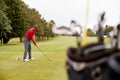 Mature Male Golfer Preparing To Hit Tee Shot Along Fairway With Bag Of Clubs In Foreground Royalty Free Stock Photo