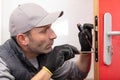 mature male lockpicker fixing door handle at home Royalty Free Stock Photo