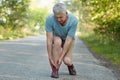 Mature male pulled his leg during outdoor training, suffers from terrible pain, poses outside. Displeased senior man pensioner has