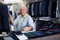 Mature male tailor takes measurement from his jacket using measuring tape