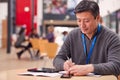 Mature Male Teacher Or Student With Digital Tablet Working At Table In College Hall Royalty Free Stock Photo