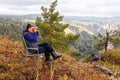 A mature male tourist sits on top of a mou-ntain and admires the picturesque morning Ural view.