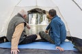 Mature male tourists sit in a tent and admire the beautiful Atysh waterfall